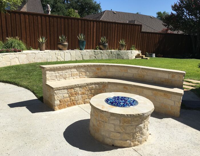 A custom stone retaining wall, gas fire pit and landscaping that we designed and built