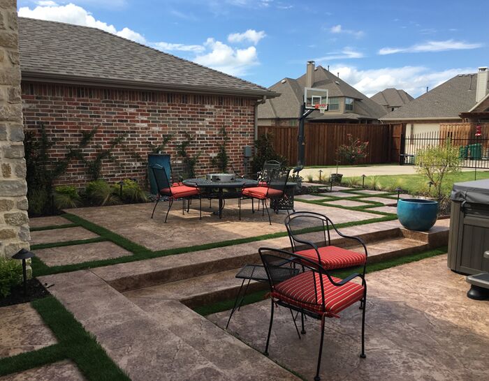 A custom stamped concrete patio, artificial turf and landscaping that we designed and built